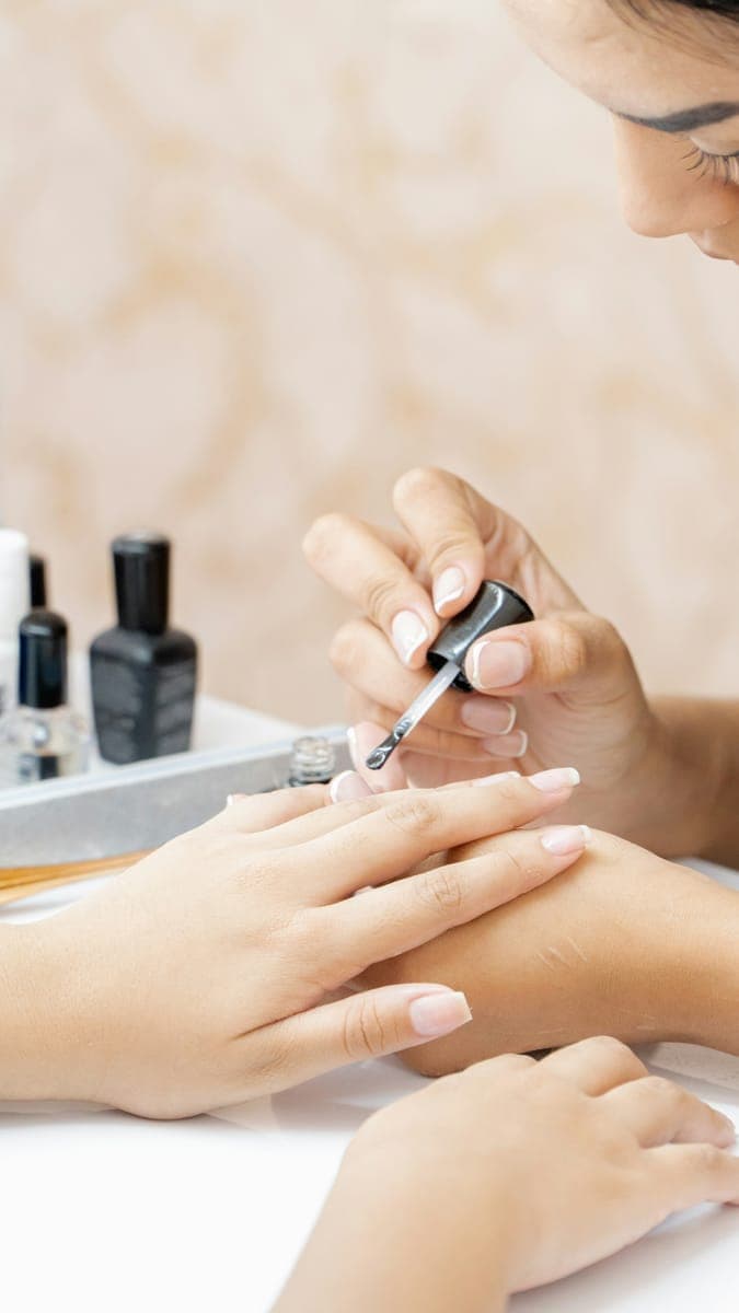 Une professionnelle applique du vernis pendant une manucure.