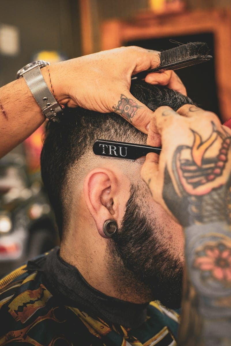 Un barbier travaille avec précision sur la coupe de son client.